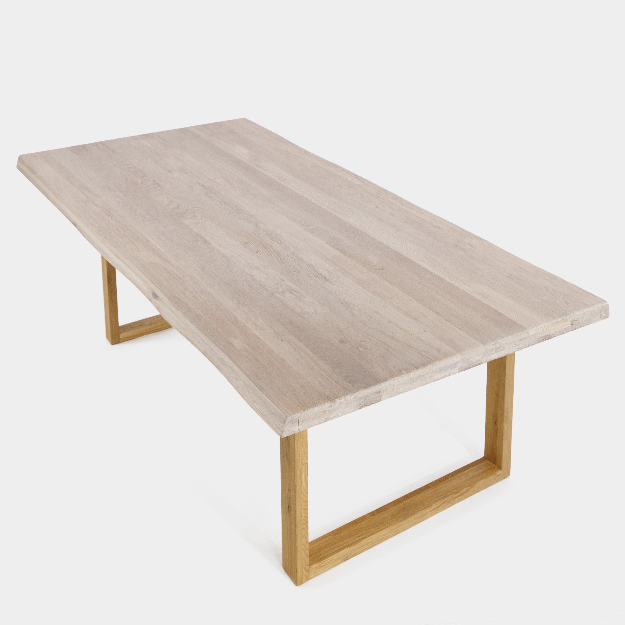 Mesa de comedor Avara de roble macizo blanqueado con patas en U de roble, canto ondulado