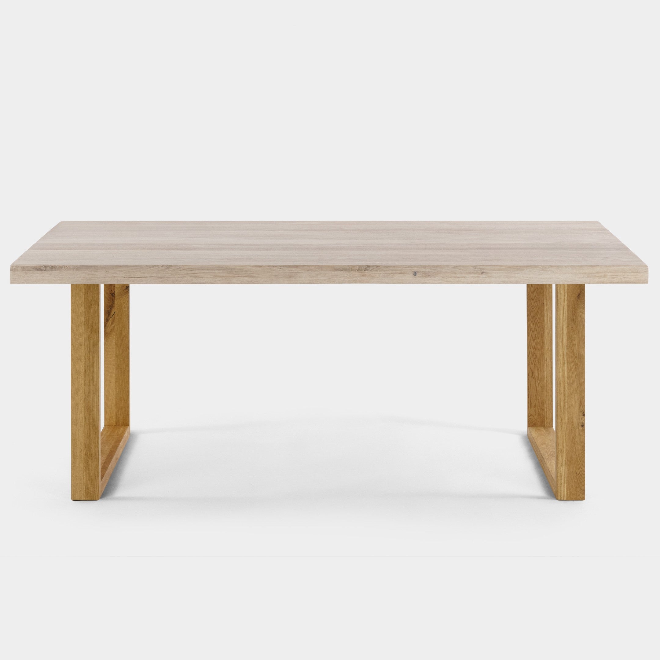 Mesa de comedor Avara de roble macizo blanqueado con patas en U de roble, canto ondulado